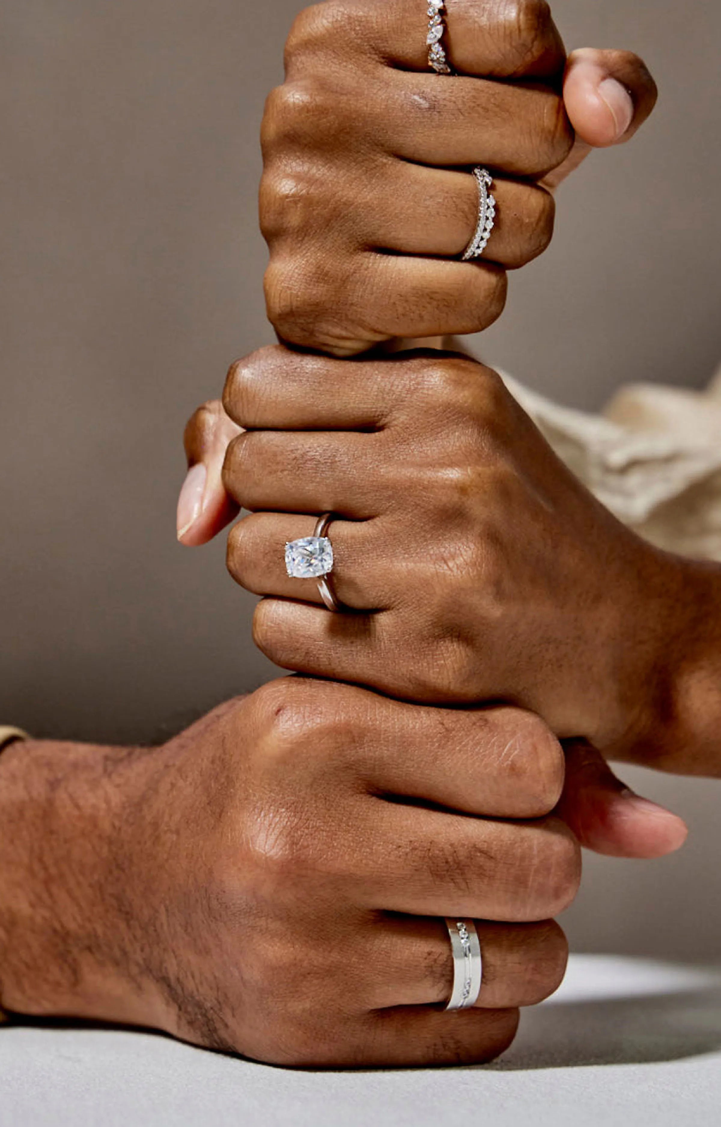 Three hands wearing different types of rings